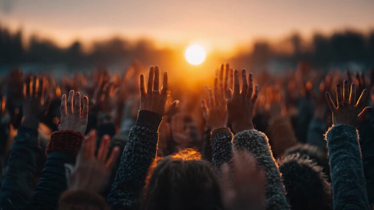 A Vibrant Crowd Celebrating at Sunset, Hands Raised in Unison Against a Backdrop of Glorious Golden Light, Reflecting Joy and Unity in a Shared Moment