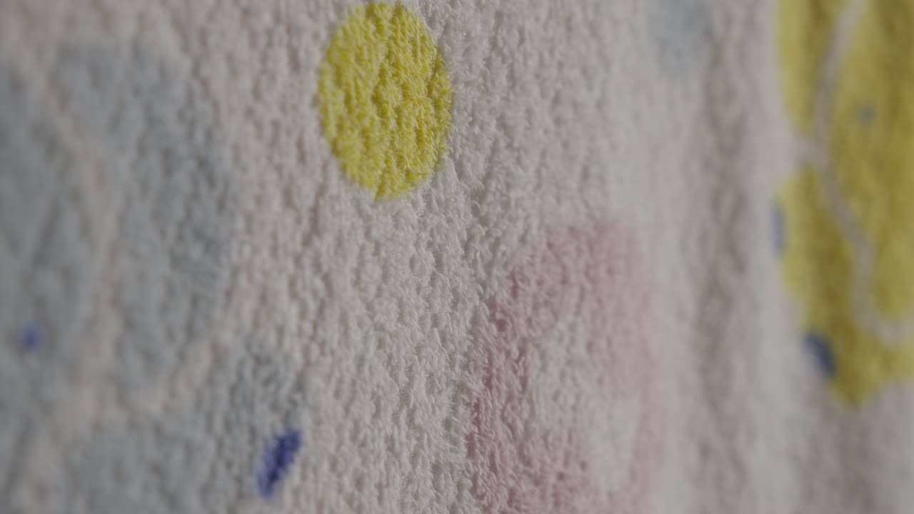 A hand gently touches a textured wall with colorful abstract shapes and a soft focus background