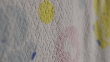 a hand gently touches a textured wall with colorful abstract shapes and a soft focus background