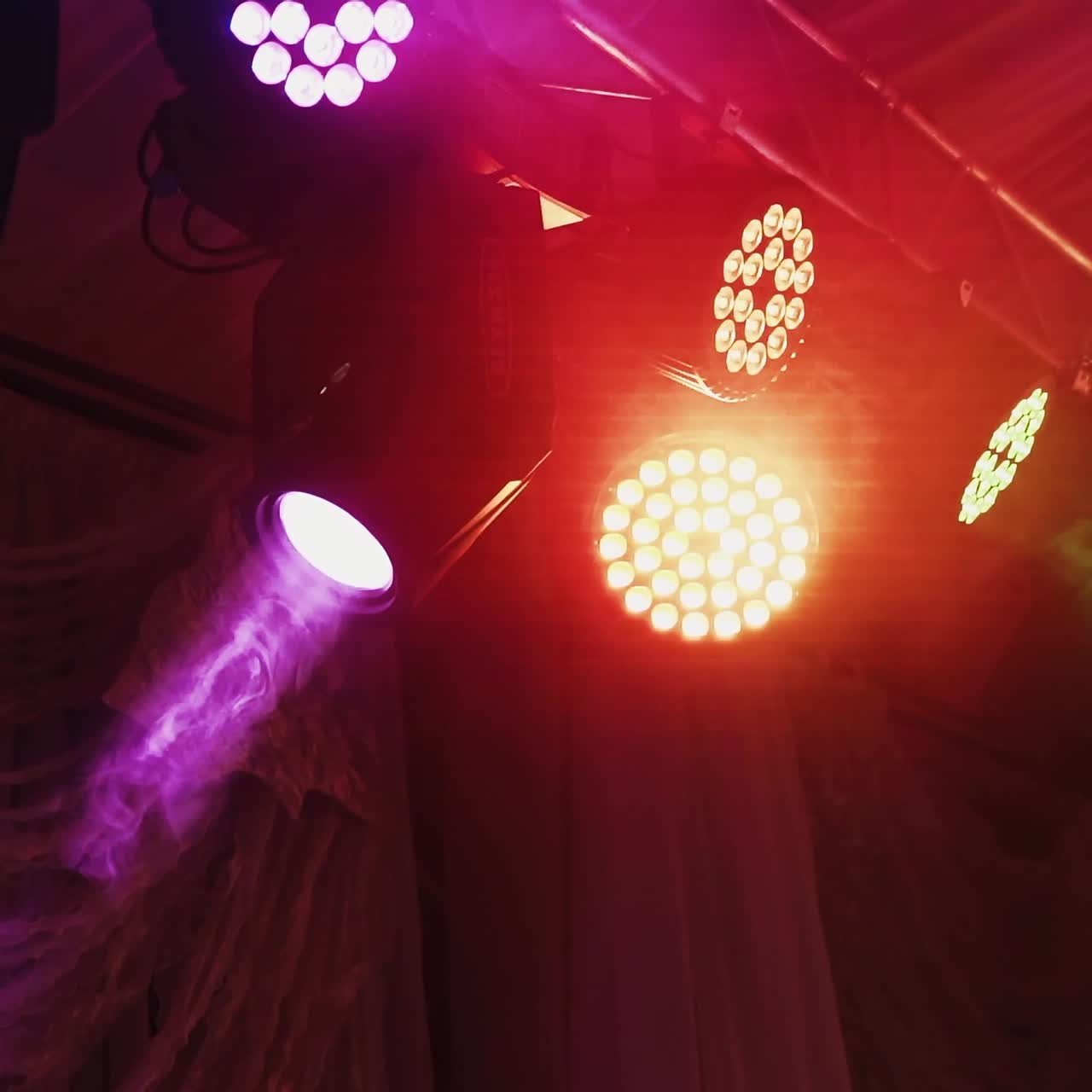 Musical farm in the night club. Colorful spotlights hang under hall ceiling and rotating with bright lights at darkness.