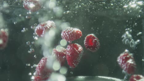 Rote-Himbeeren-Fallen-In-Einen-Behälter-Mit-Sprudelndem-Wasser