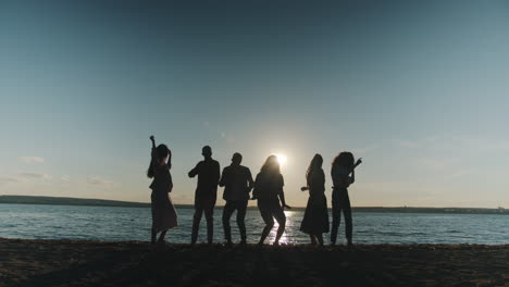 amigos bailando al atardecer en la playa