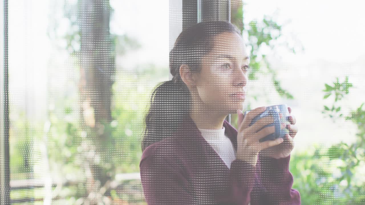 Mid adult woman beside glass door sipping from blue mug then scanning foliage for health