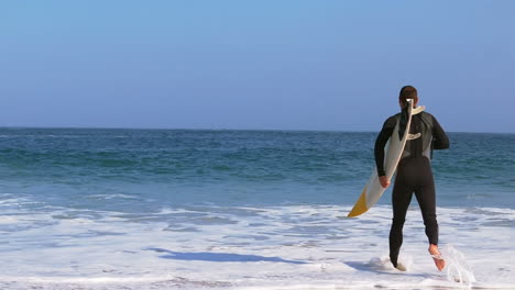 man in wet suit running into water