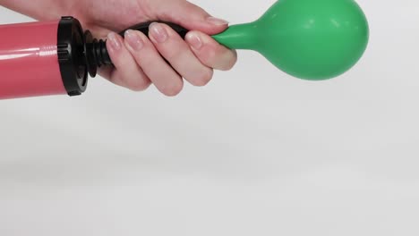 a sequence showing a green balloon being inflated using a hand pump, highlighting the inflation process.