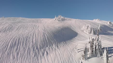 vista aérea de una moto de nieve dejando huellas en la nieve en revelstoke, columbia británica
