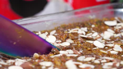 rebanar un trozo de pastel de postre de frutas secas con virutas de nuez y un gran cuchillo morado