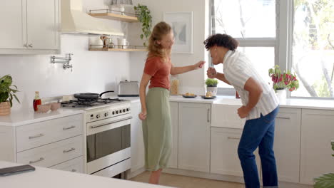 happy diverse couple dancing together in bright kitchen, enjoying morning routine, at home