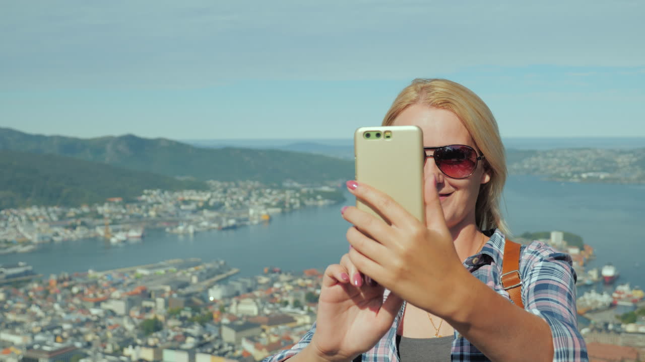 mujer turista tomando fotos de sí misma en el contexto de la ciudad de bergen en la gira de noruega