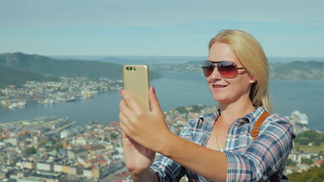 woman tourist taking pictures of herself against the background of the city of bergen in norway tour