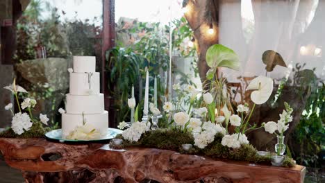 white tiered cake with natural flowers on rustic wooden table for wedding reception