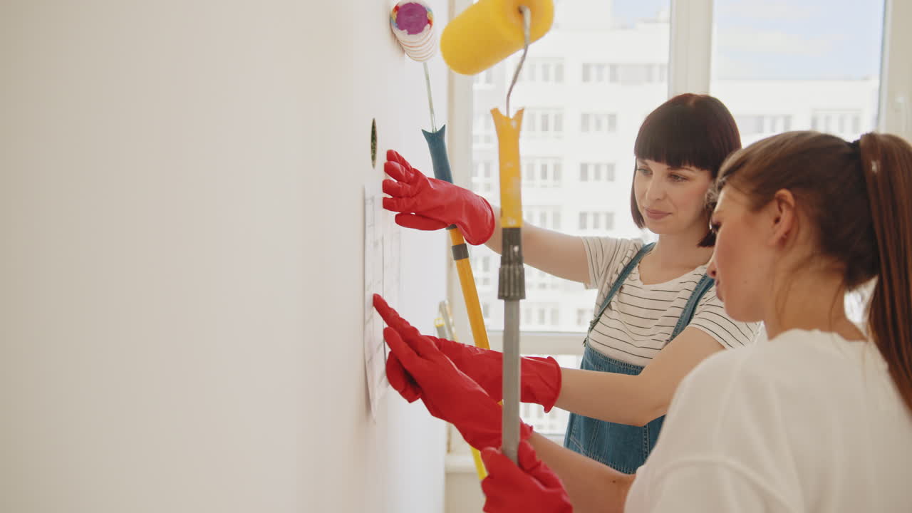 dos mujeres pintando una pared, planeando el proyecto.