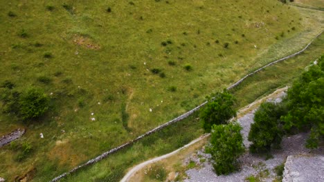 Aerial-view-descending-down-lush-rolling-Peak-district-valley-in-scenic-rural-English-countryside