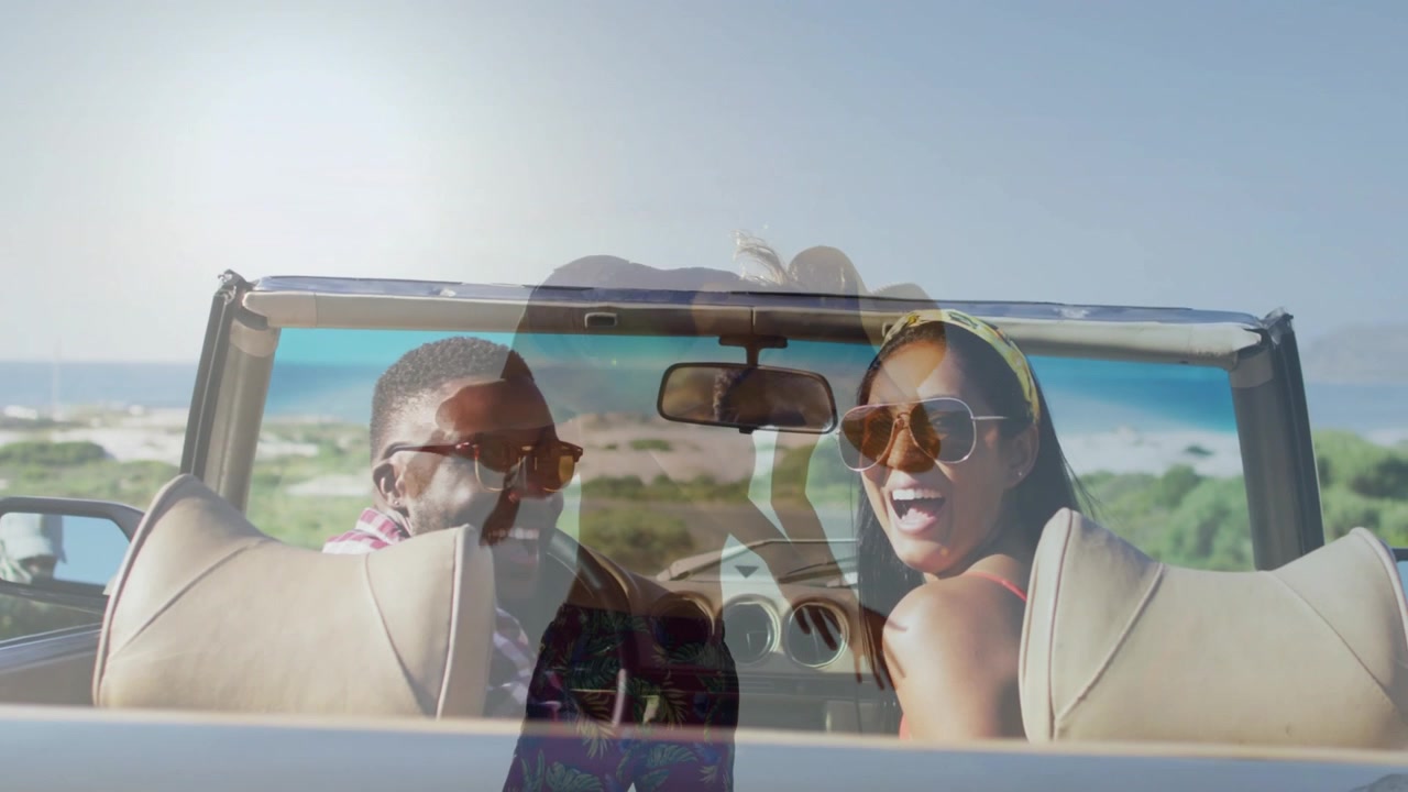 Passenger turning back and waving, driver laughing, faint hat overlaying convertible ocean travel