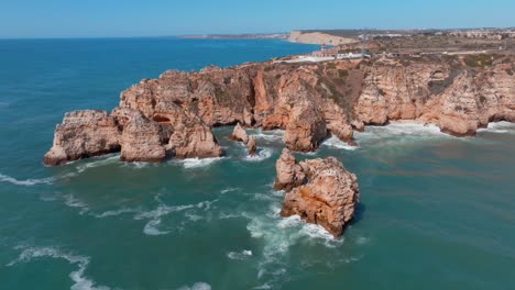 rocky ocean wave ripples around ponta da piedade lagos algarve portugal, aerial orbit