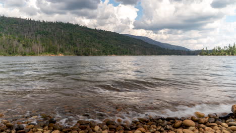 time lapse of boats and canoes passing by on a windy lake with storm clouds rolling in over mountains in the background