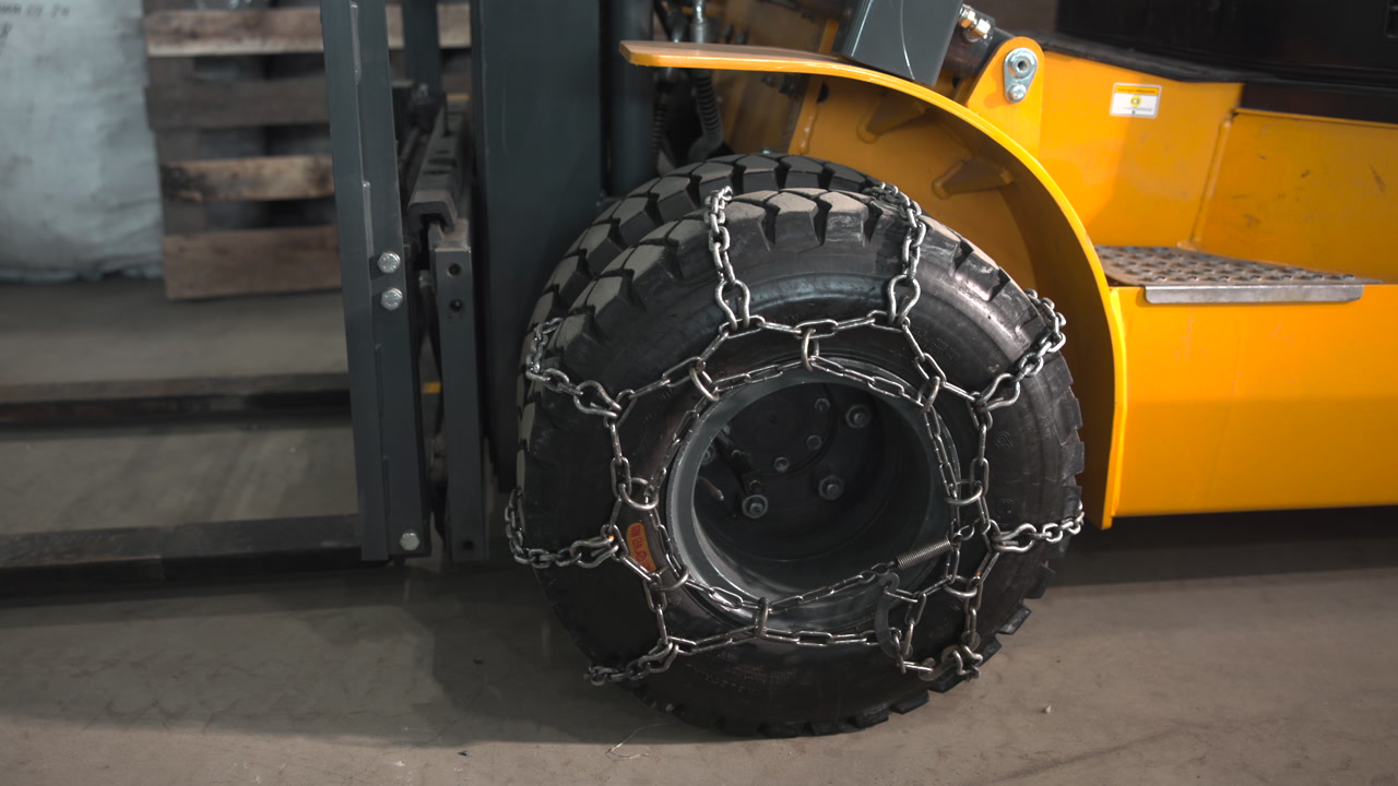 Close Up Forklift Wheel With Chains Warehouse Maintenance Scene Showing Technician Preparing Tire Chains . Media