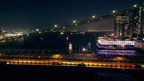 Panorámica-Hacia-La-Izquierda-Cruzando-El-Río-Desde-El-Lado-De-Manhattan-Del-Puente-De-Brooklyn-Por-La-Noche