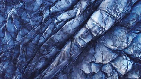 Aerial:-descending-into-Glaciers-deep-crevasses-and-jagged-ice-formations,-evidence-of-the-impact-climate-change-has-on-the-constant-movement-and-transformation-of-this-natural-wonder