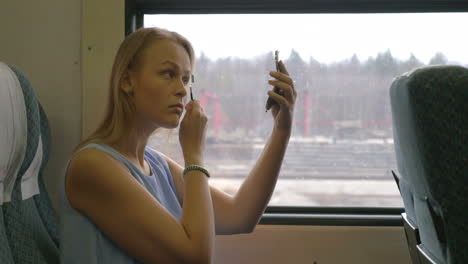 young woman putting make-up in train