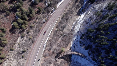 Top-down-view-of-a-car-driving-along-a-snowy-mountain-road