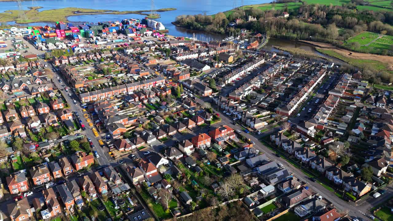 Flugschwenk über den Vorort Totton westlich des Flusses in Southampton, England, mit Autos auf den belebten Straßen und Sonnenlicht, das sich im Winter auf dem blauen Flusswasser mit Booten darauf spiegelt