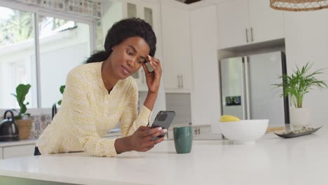 Video-of-african-american-woman-using-smartphone-in-kitchen