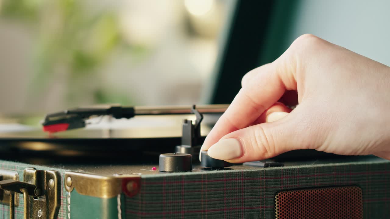 ビンテージレコードプレーヤーの音量つまみを調整する手。