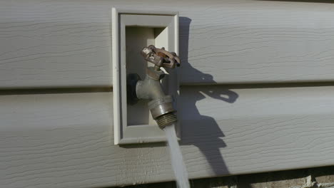 freshwater spigot on the side of a home with water pouring out