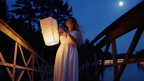 woman with lantern on a bridge at night