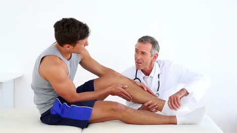 mature doctor touching sportsmans injured ankle