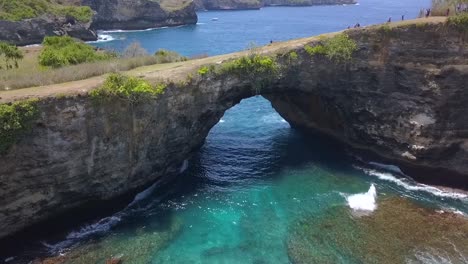 vuelo con vista aérea de un dron de 1 millón de dólares sobre la playa rota de un puente natural en nusa penida en bali, indonesia