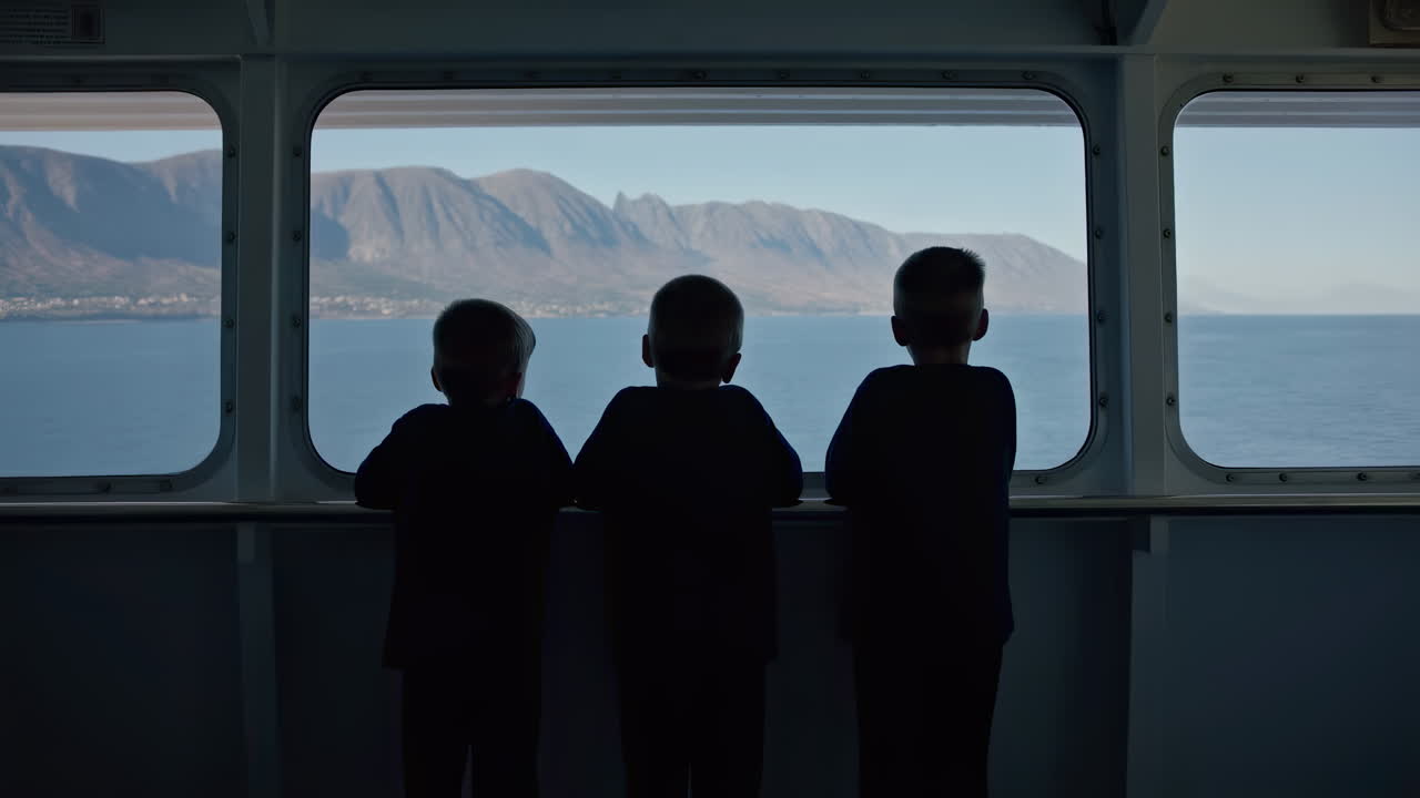 Three Boys Silhouetted Looking Out Ferry Window at Sea and Mountains