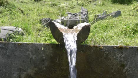 kleiner trinkbrunnen mit uraltem felsen aus einer bergquelle