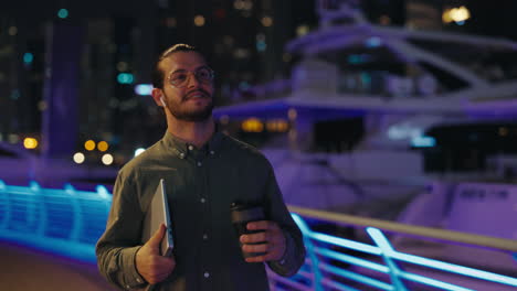 businessman walking at night with laptop and coffee