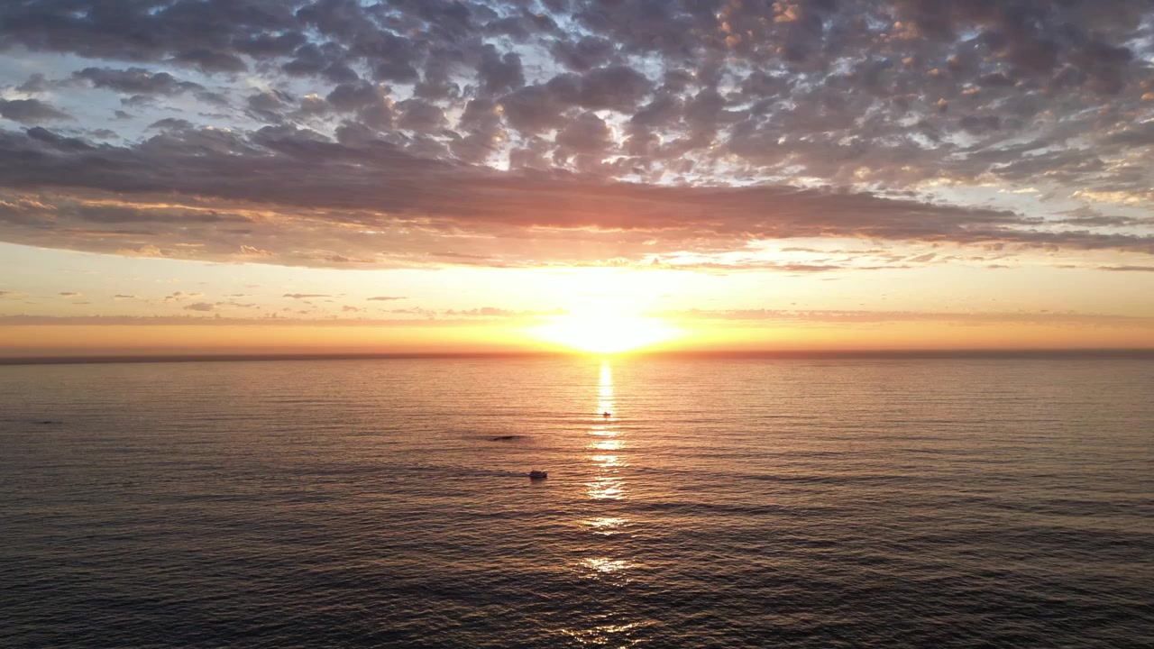 Betagende gylden solnedgang over det rolige Atlanterhav ud for Cape Town, Sydafrika, med solrefleksion, der glimter hen over vandoverfladen og både
