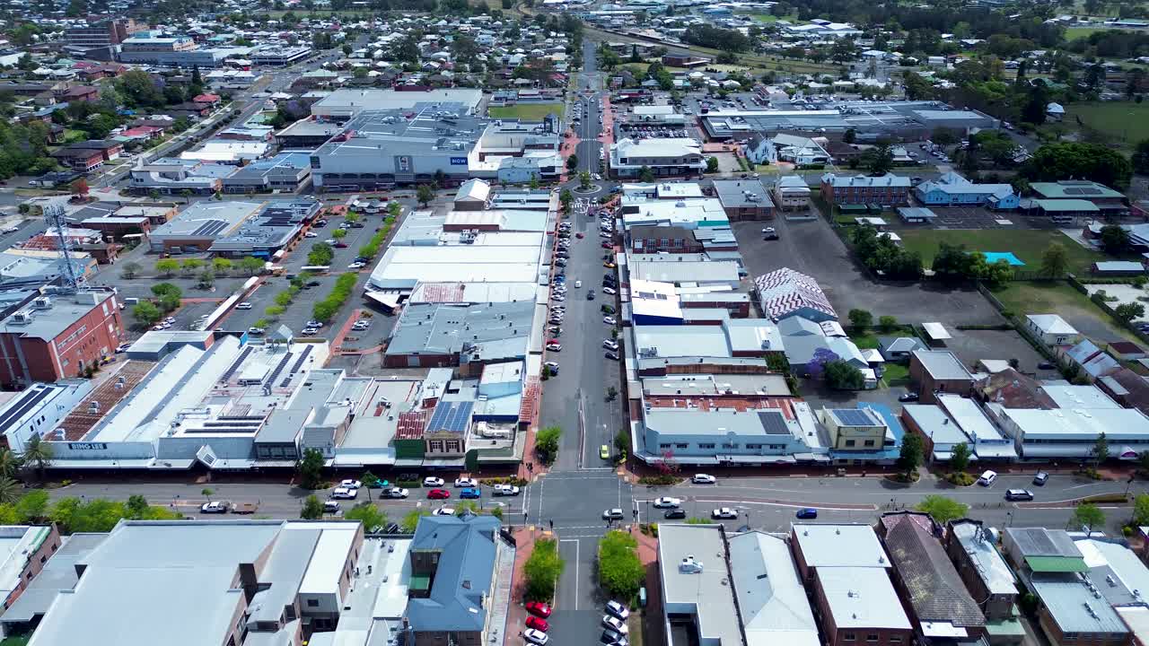 Drone aerial landscape of Taree urban downtown showing car vehicles driving through main road with traffic lights and others parked along street near shop buildings in Australia tourism infrastructure