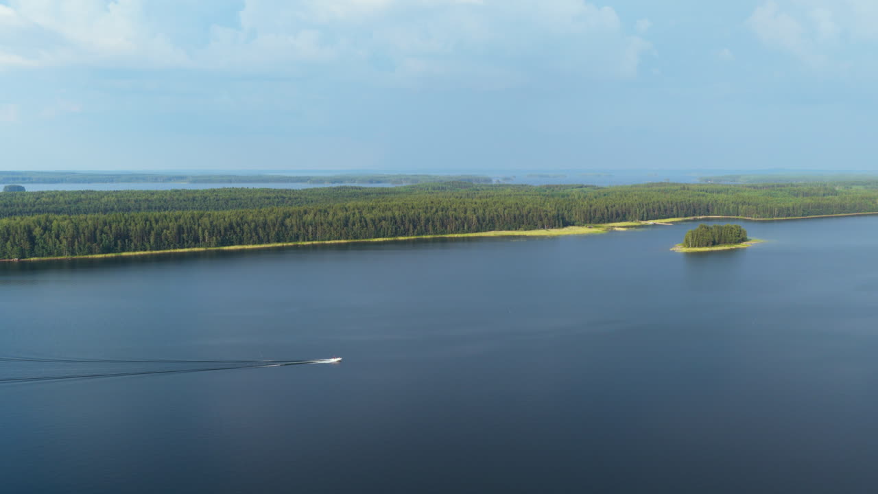 Panoramic drone shot following a boat driving on lake Saimaa, sunny day in Finland
