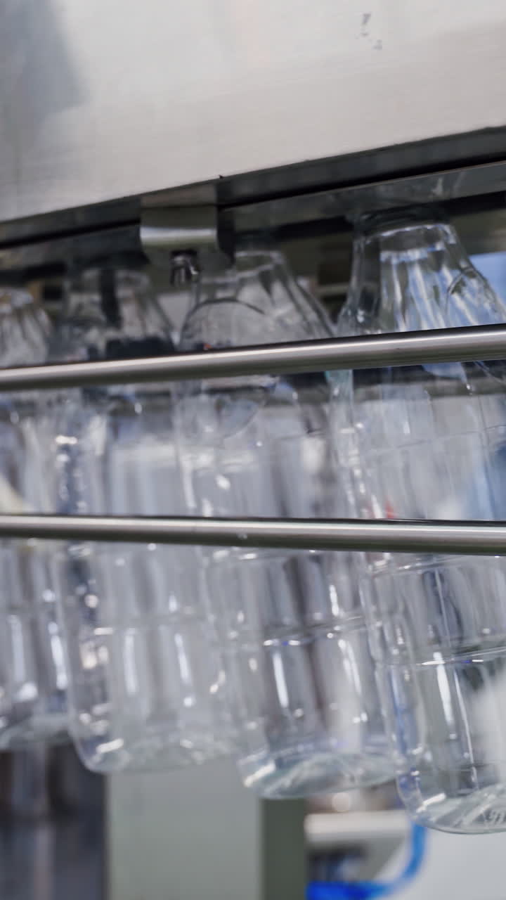 Empty plastic bottles on conveyor line. Bottle production line. Plastic bottles for liquid products on conveyor belt in modern milk plant. Vertical video