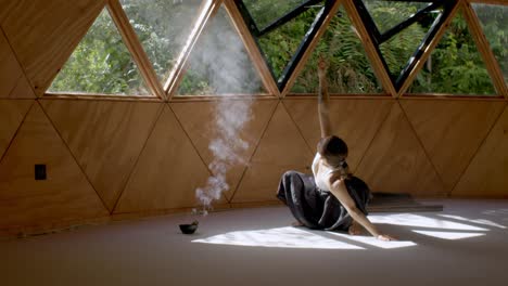 sage cleans burns and spreads smoke in air with mindful yoga poses with a latina woman in a peaceful outdoor geometric studio