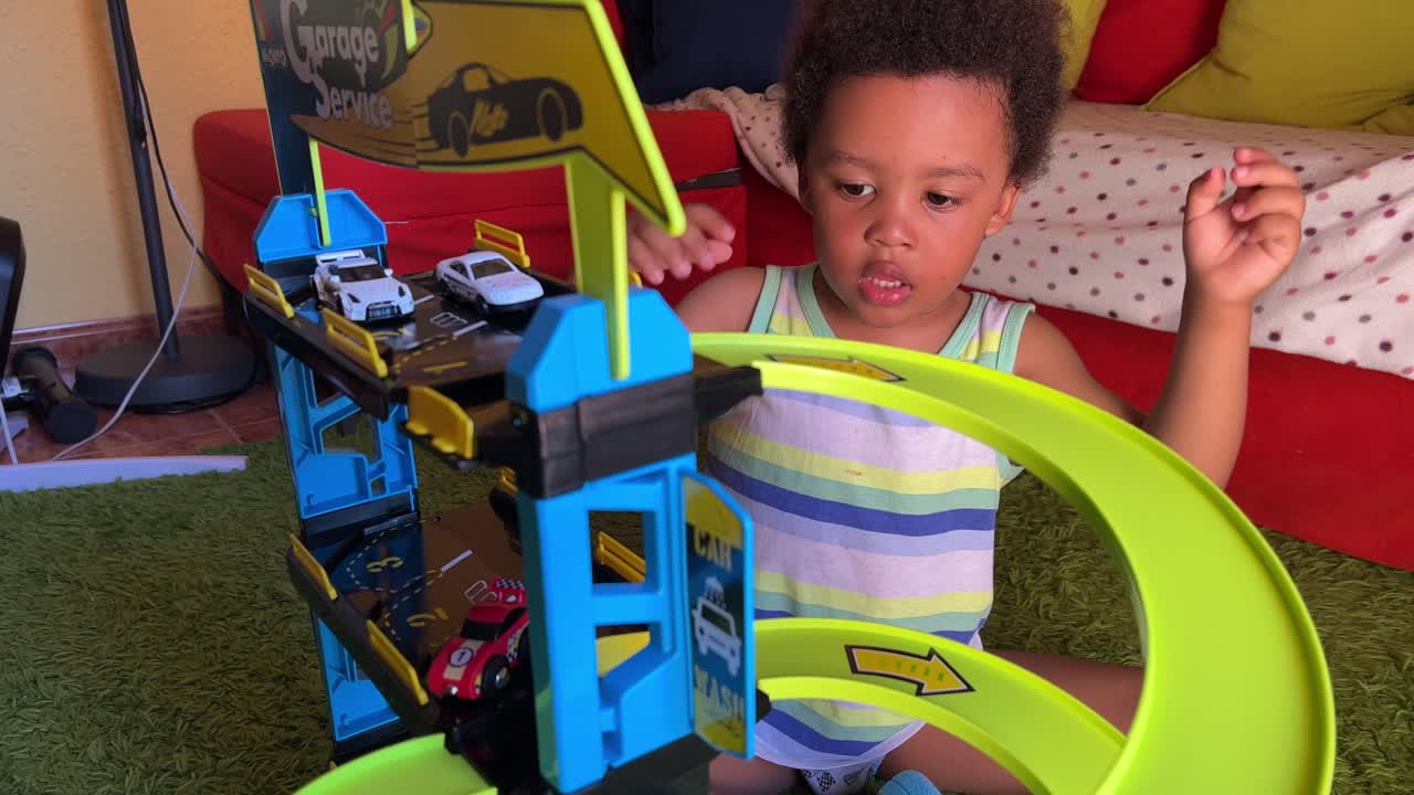 Adorable 3-year-old black toddler amused playing with his toy garage at home