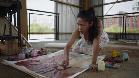 woman painting on a large canvas in an art studio