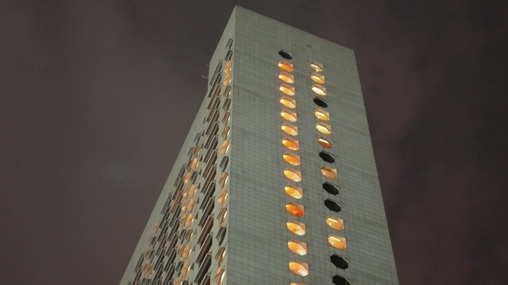 Edifícios modernos de hotéis e shoppings ao redor da Marina Square brilham através de um céu noturno nebuloso perto do circuito de rua da Fórmula 1, capturando a atmosfera vibrante do evento de grande prêmio urbano
