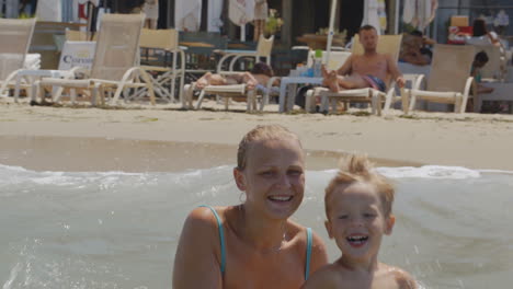 mother and son jumping with waves in sea