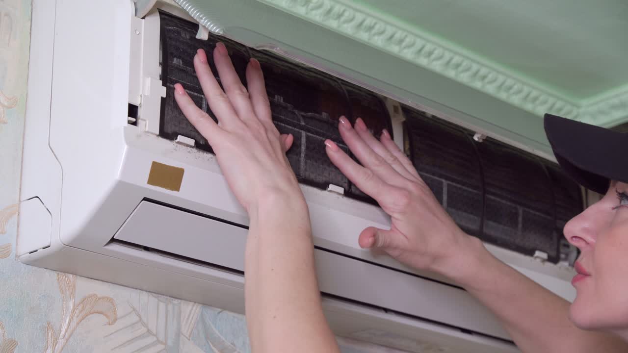Mani di donna controllano il grado di contaminazione dei filtri dell'aria di un condizionatore domestico