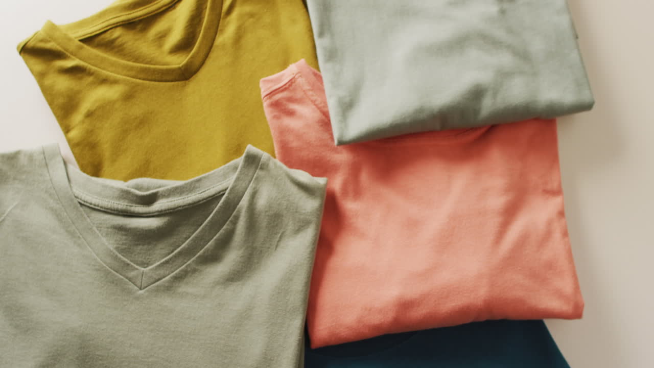 Video of close up of folded t shirts on white background