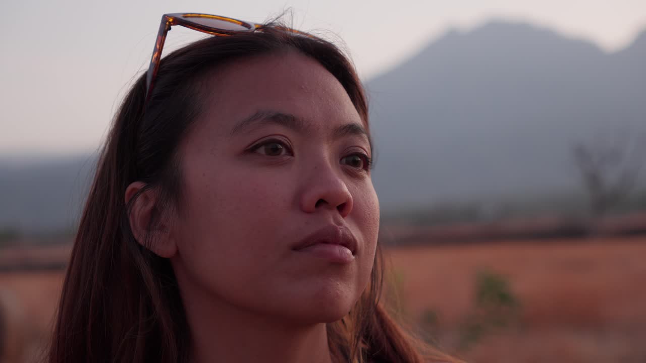 그녀는 새벽의 가장자리에 서 있습니다, 젊은 아시아 여성, 빛으로 반이는 눈