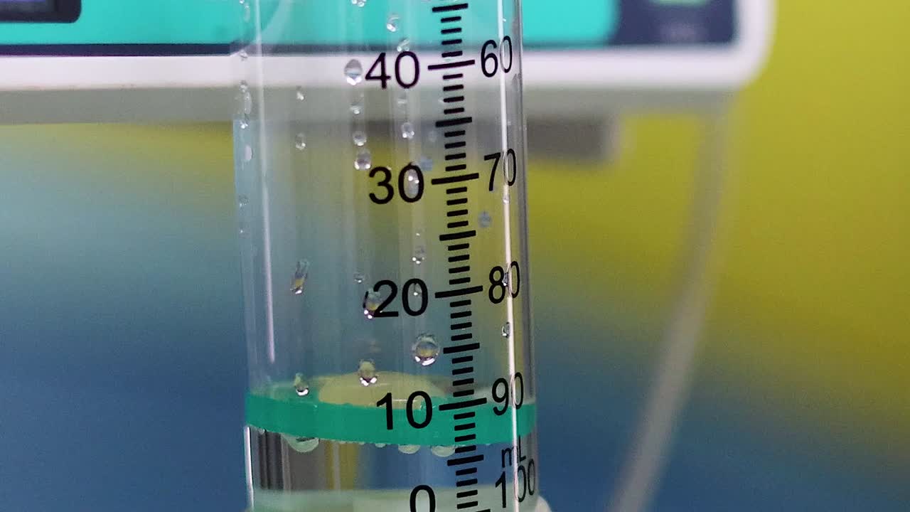 Close-up detalhado de uma câmara de gotejamento médico mostrando os níveis de líquido e as marcações da escala de medição