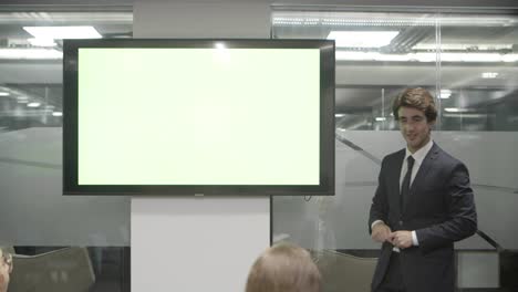 confident man talking while standing near screen