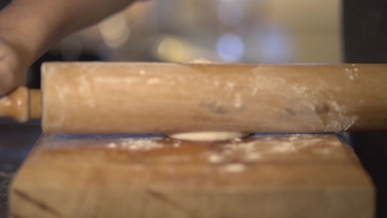Front View Of A Baker Hand's Using Rolling Pin To Flatten The Dough On The Wooden Board - Slow Motion Shot